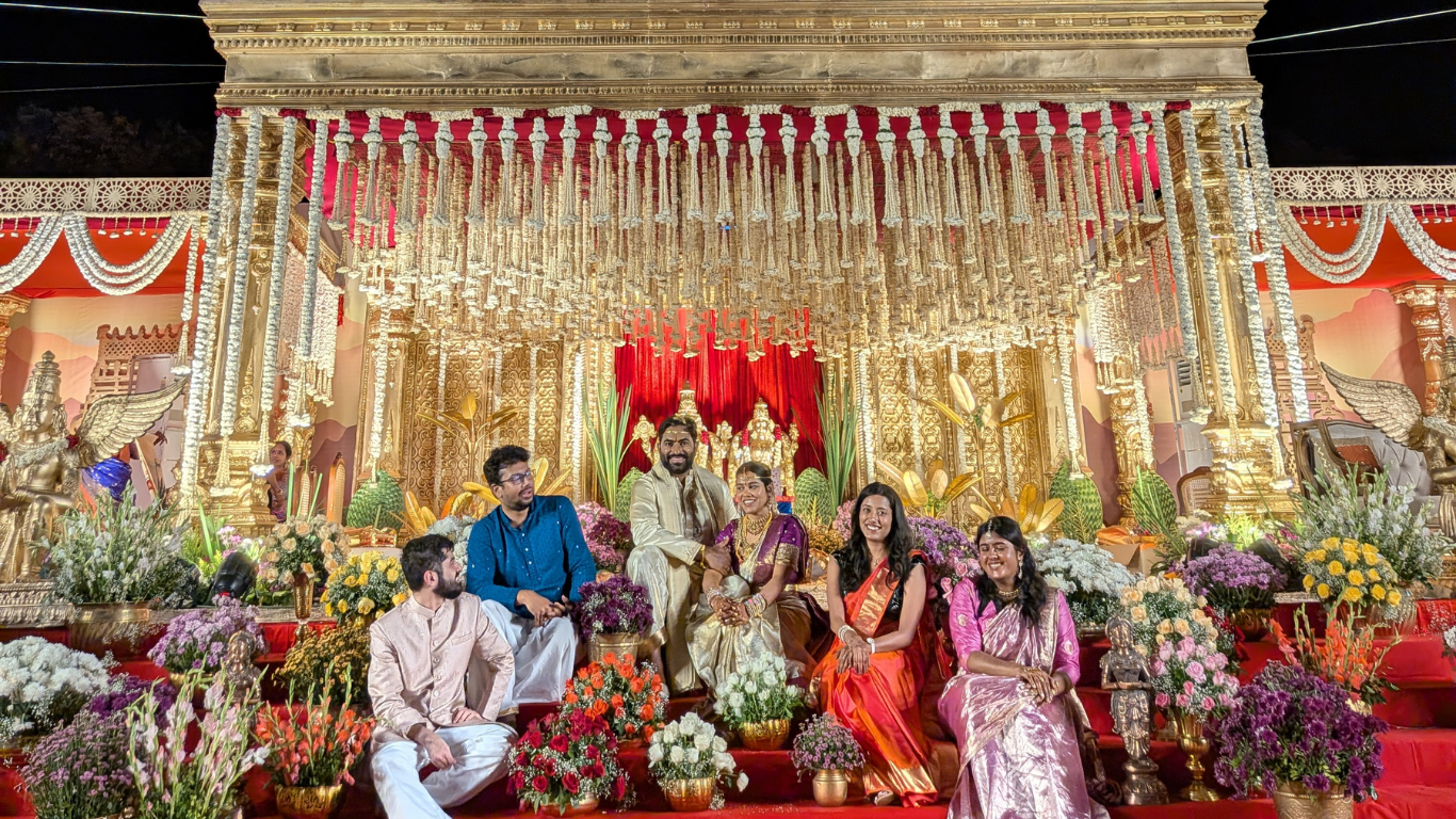 Family portrait on the illuminated golden mandap with floral arrangements
