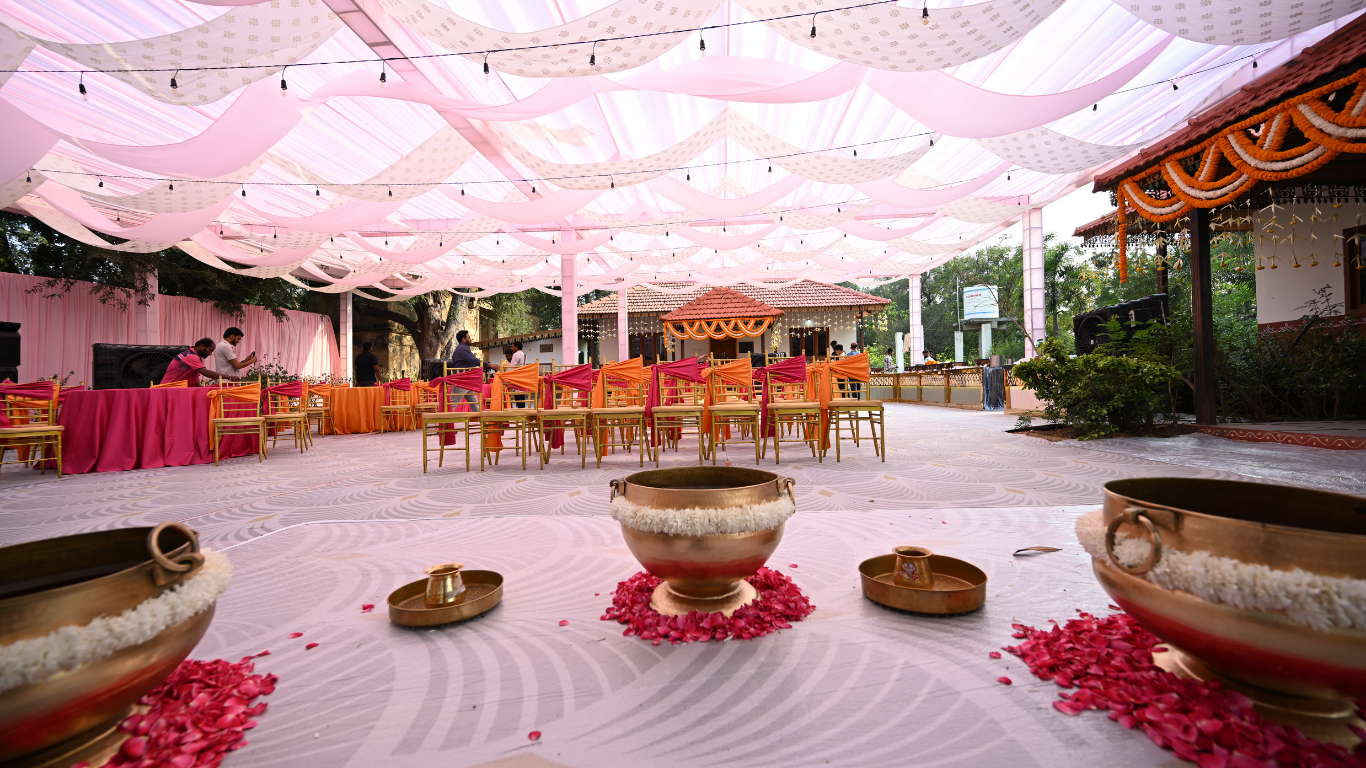 Haldi ceremony hall with pink draped canopy, fairy lights and chiavari chairs
