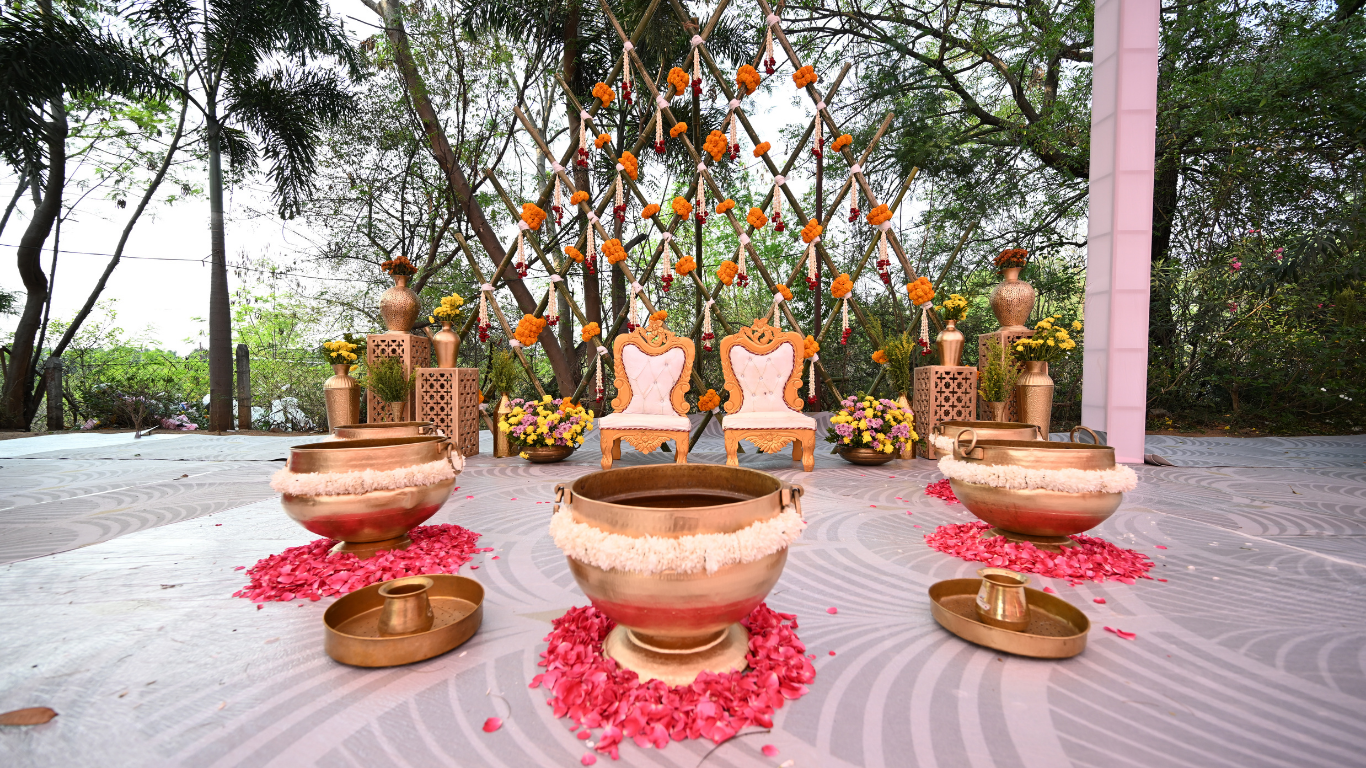 Haldi ceremony backdrop with marigold garlands and brass urli bowls with rose petals