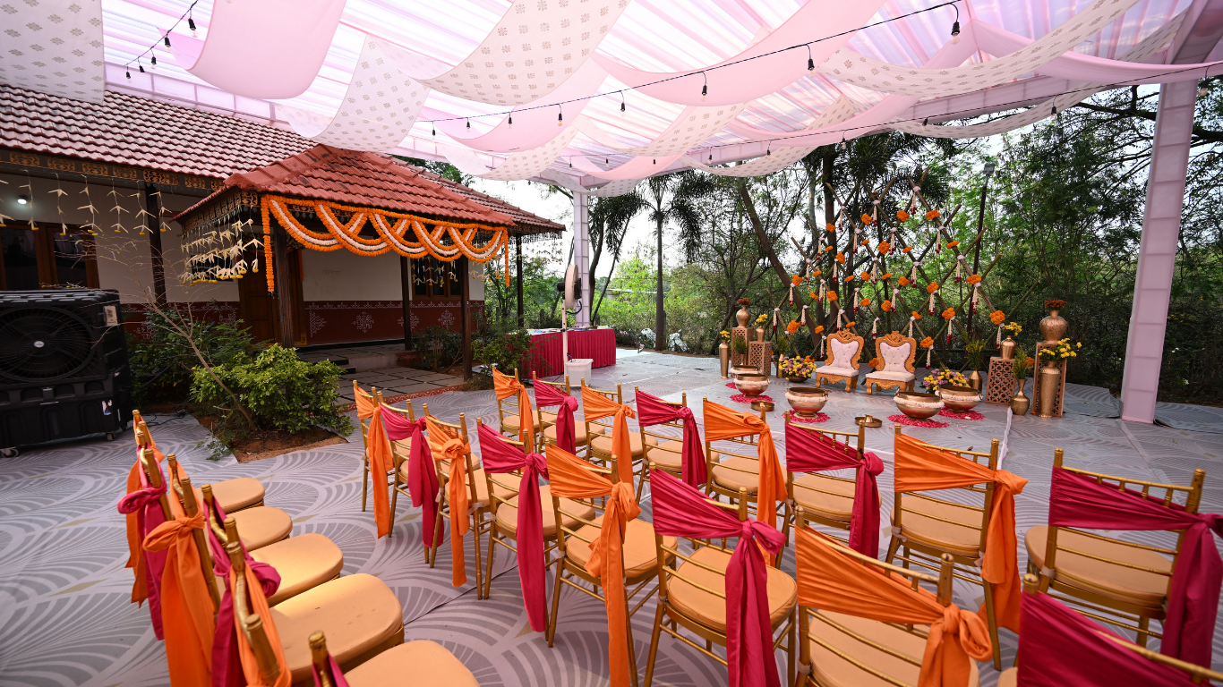 Haldi guest seating with orange and pink sashes facing the floral mandap