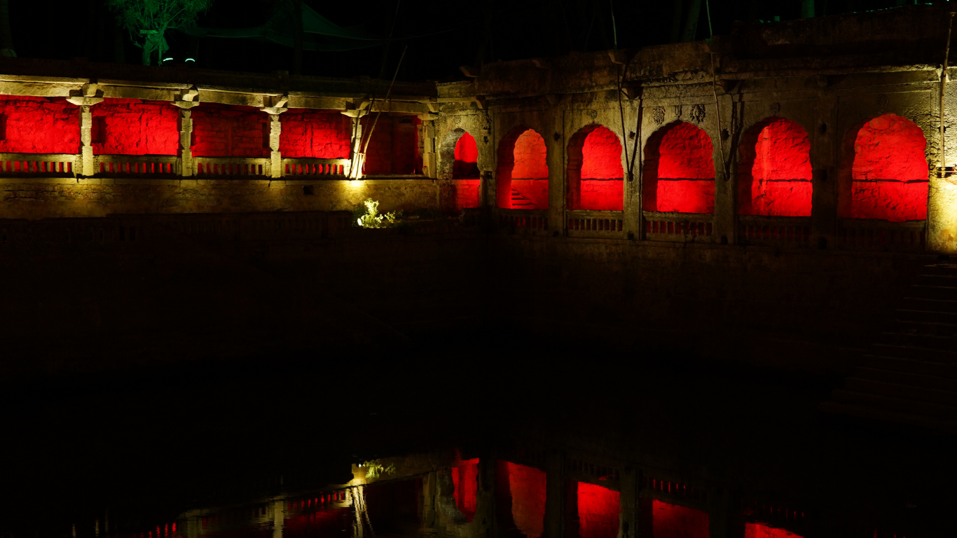 Ammapalli Temple lake-side colonnade illuminated with red lights at night with reflections in the water