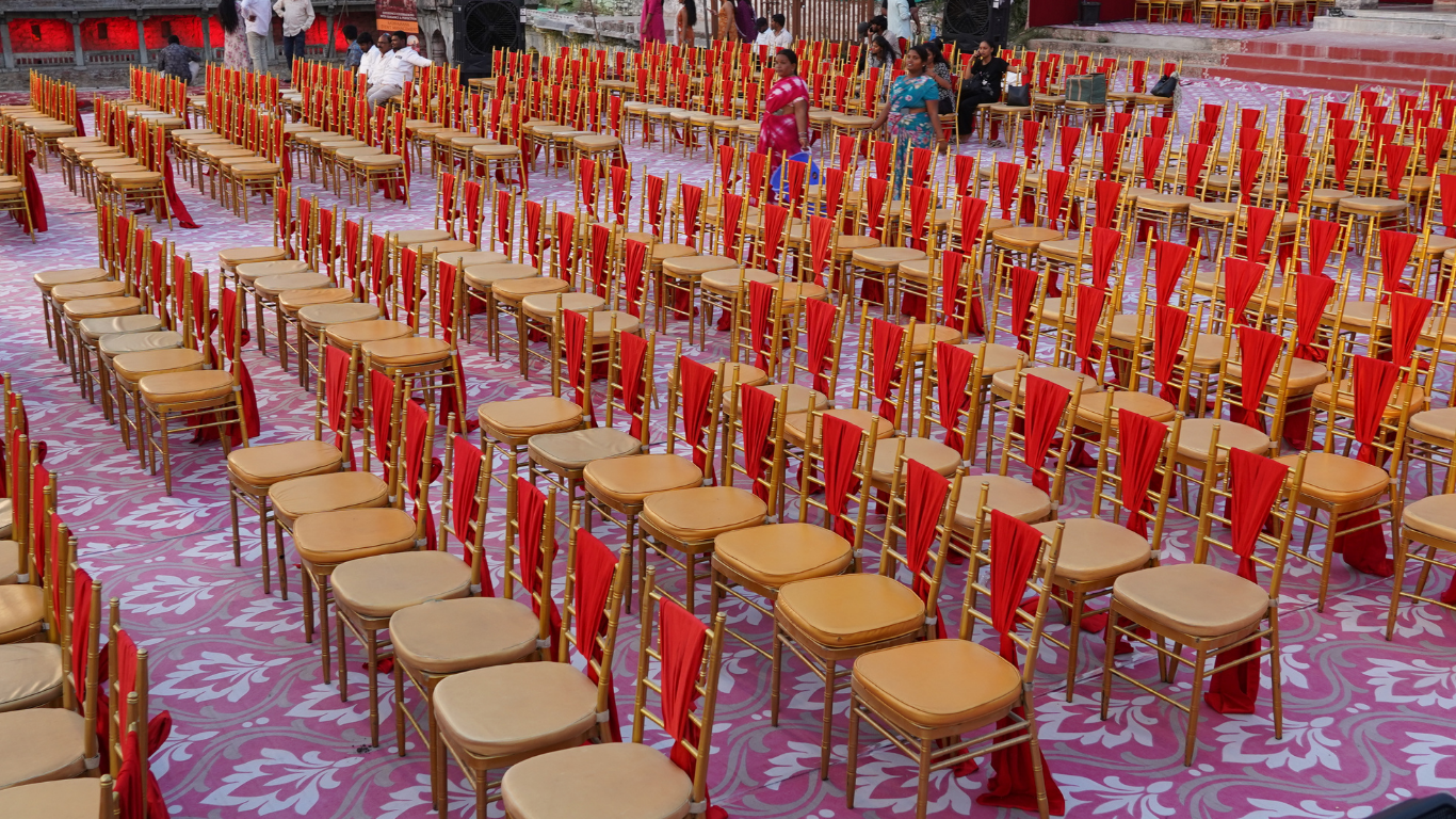 Rows of gold chiavari chairs with red sashes on patterned floor for the ceremony